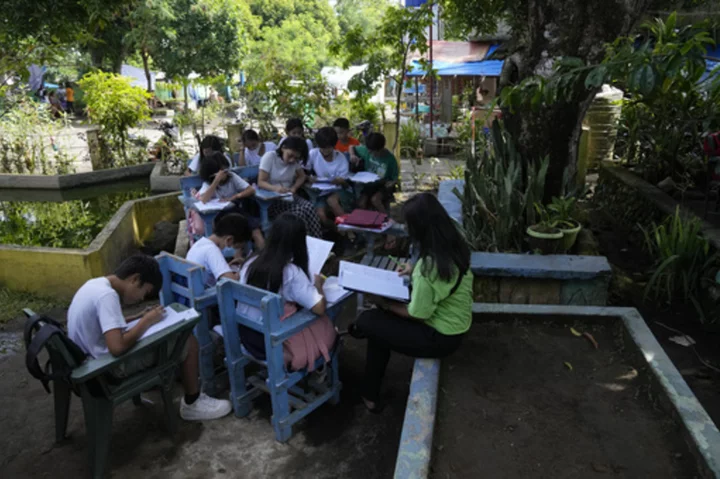 Students meet under trees as schools shelter villagers displaced by Philippine volcano