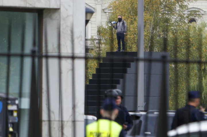 Police in Warsaw detain a man who climbed a monument and reportedly made threats