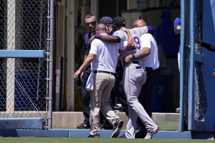 Rockies' Jurickson Profar slams into the outfield wall at Dodger Stadium, injuring his left knee