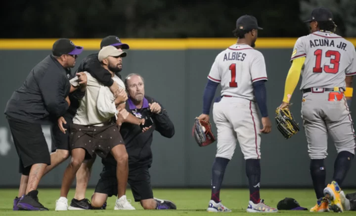 Fans run onto field and one makes contact with Atlanta Braves star Ronald Acuña Jr.